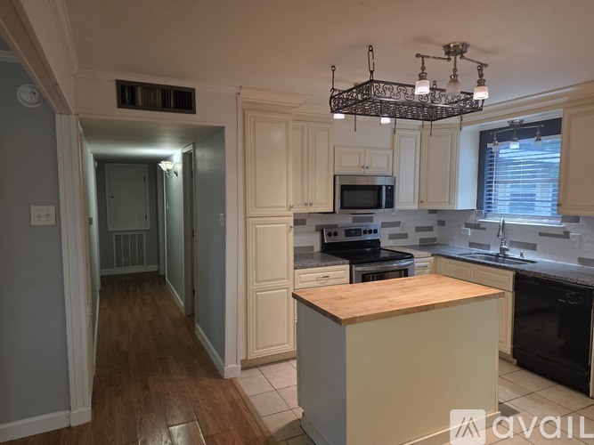A kitchen with a wooden counter top and white cabinets.