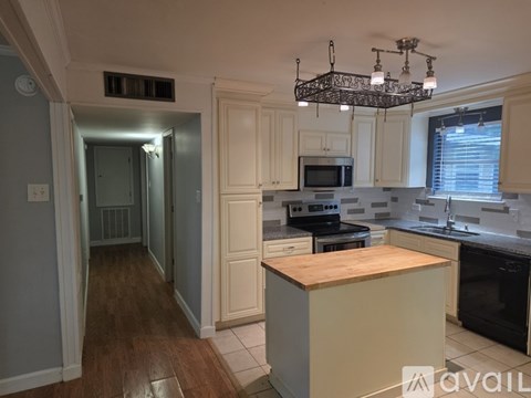 A kitchen with a wooden counter top and white cabinets.