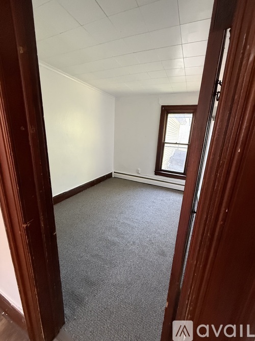 A room with a carpeted floor and a window with a white frame.