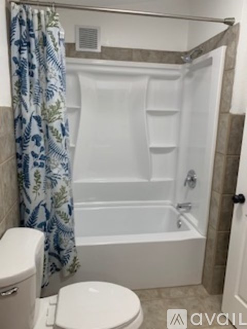 A white toilet sits next to a bathtub in a bathroom.