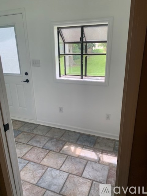 A tiled floor leads to a white door and window.