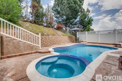A pool with a white fence and a hill in the background.