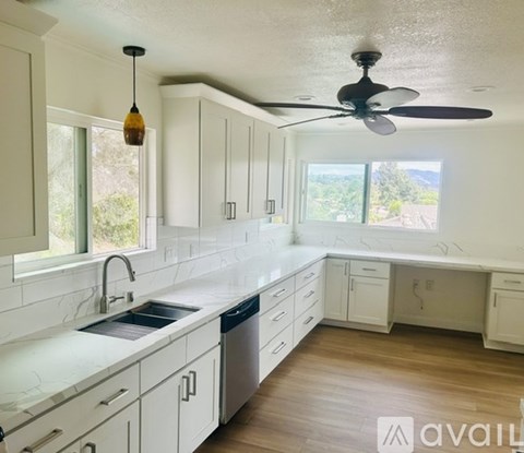 A kitchen with white cabinets and a black ceiling fan.