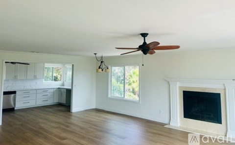 A spacious living room with a fireplace and a ceiling fan.