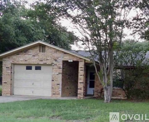 A brick house with a white garage door and a tree in front.