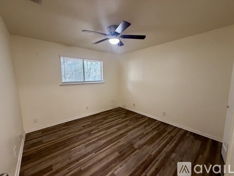 A room with a ceiling fan and wooden flooring.