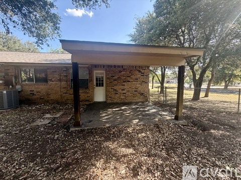 A small building with a porch and a door is surrounded by trees.