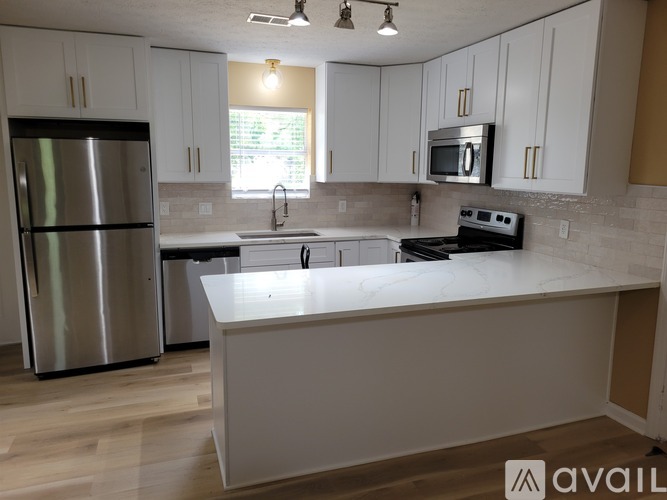 A kitchen with white cabinets and a stainless steel refrigerator.