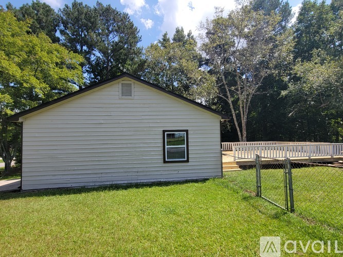 A small white house with a window and a fence in front of a grassy area.