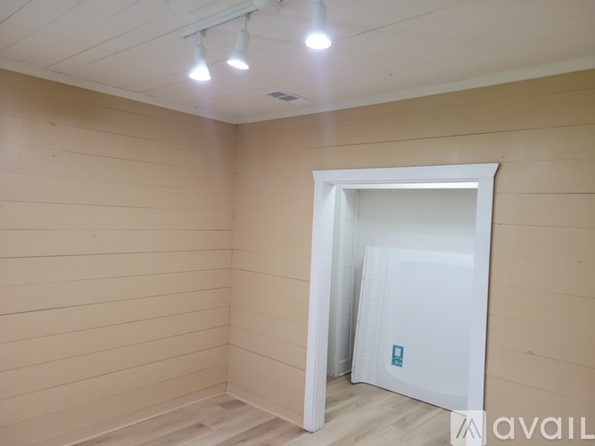 A room with a white door and a wooden floor.
