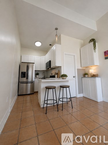 A kitchen with white cabinets and a tiled floor.