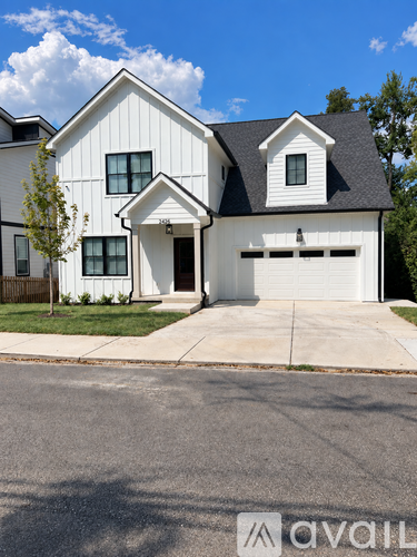 A white house with a black roof and a garage door.
