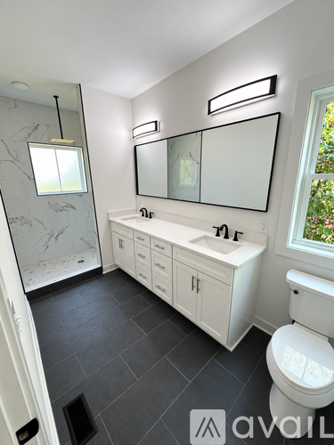 A bathroom with a toilet, sink, and mirror.