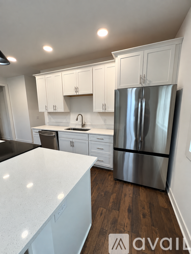 A kitchen with white cabinets and a stainless steel refrigerator.
