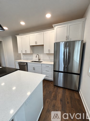 A kitchen with white cabinets and a stainless steel refrigerator.