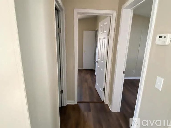 A hallway with a white door and a white wall.