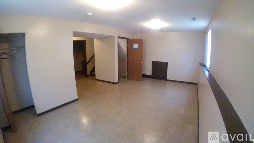 A spacious room with a door, a window, and a wall-mounted coat rack.