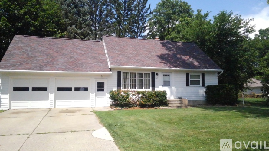 A white house with a red roof and a garage door.