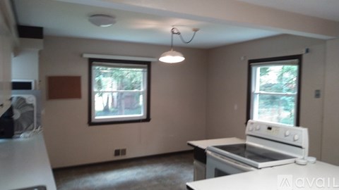 A kitchen with a white stove top oven and a window with a view of trees.