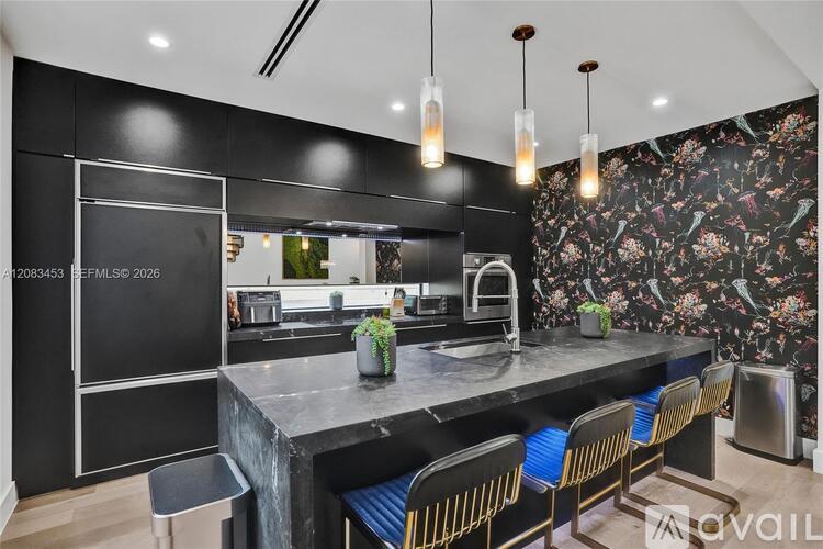 A modern kitchen with a black countertop and bar stools.