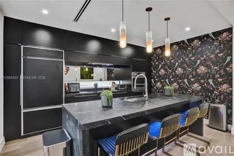 A modern kitchen with a black countertop and bar stools.