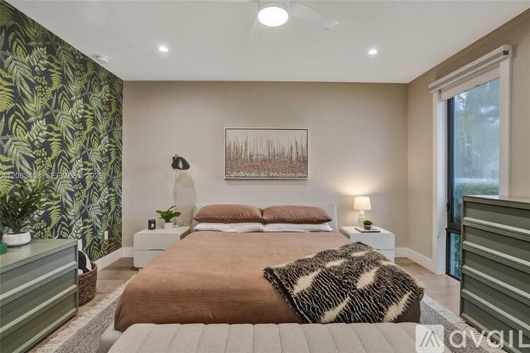 A bedroom with a large bed and a painting on the wall.