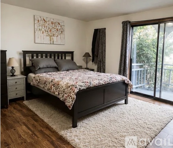 A bedroom with a large bed, a nightstand, and a painting on the wall.