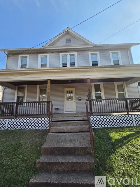 A two-story house with a front porch and stairs leading up to the entrance.
