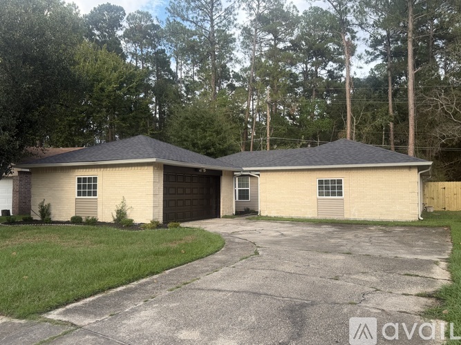 A two-story house with a garage is surrounded by trees.