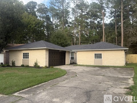 A two-story house with a garage is surrounded by trees.