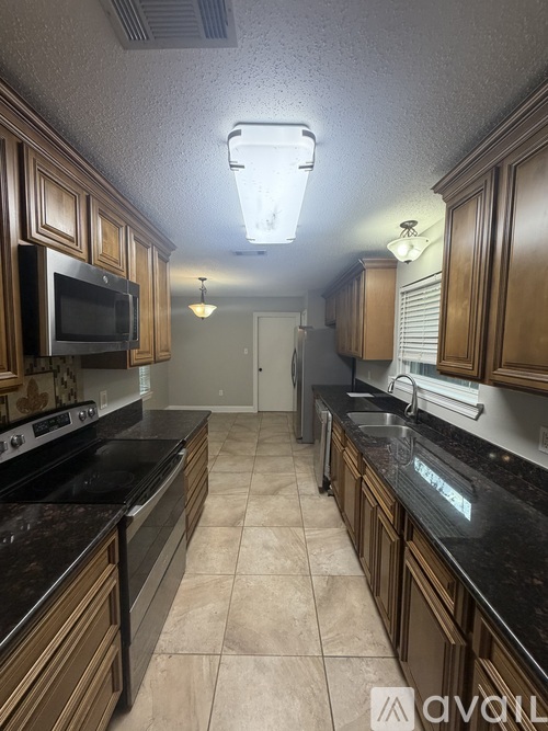 A kitchen with wooden cabinets and black countertops.