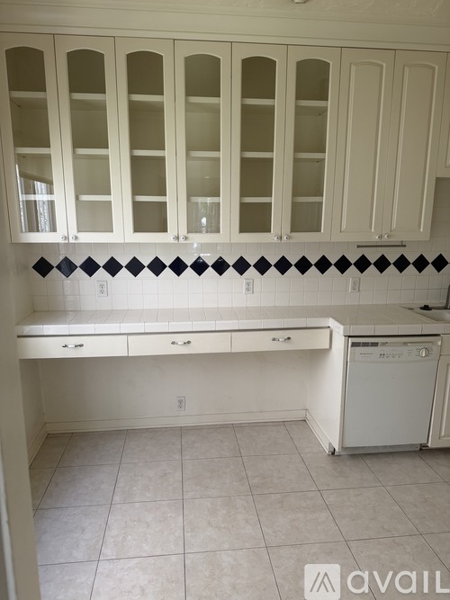 A kitchen with white cabinets and a black and white tile backsplash.
