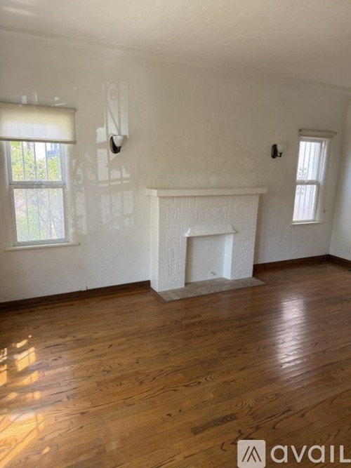 A room with a white fireplace and wooden floors.