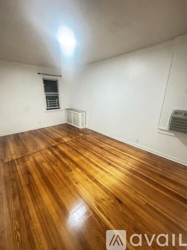 A room with wooden flooring and white walls.