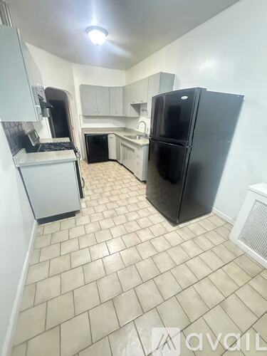A kitchen with a black fridge and white cabinets.