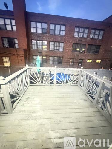A balcony with a white railing and a pool in the background.