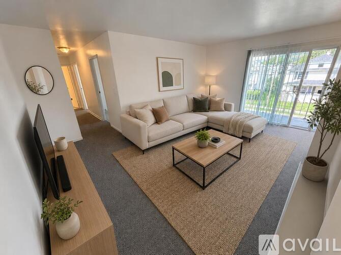 A living room with a white sofa, a coffee table, and a flat-screen TV.