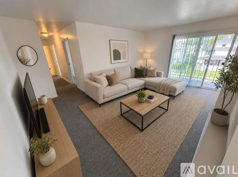 A living room with a white sofa, a coffee table, and a flat-screen TV.