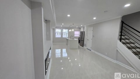 A spacious, empty hallway with a staircase on the right and a window on the left.