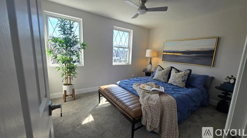 A bedroom with a bed, a bench, and a plant.