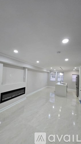A spacious, empty room with a fireplace and a large mirror on the wall.