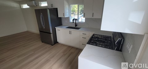 A kitchen with a black fridge and white cabinets.