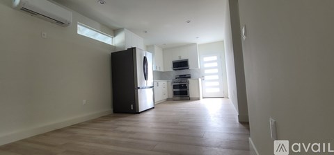 A kitchen with a black fridge and a wooden floor.