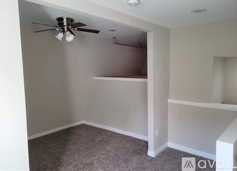 A room with a ceiling fan and a carpeted floor.