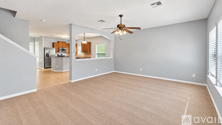 A spacious living room with a ceiling fan and lighting fixture.