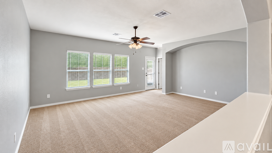 A spacious room with a ceiling fan and carpeted floor.