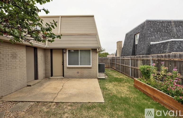 A house with a brown roof and a brown fence with a garden in front.