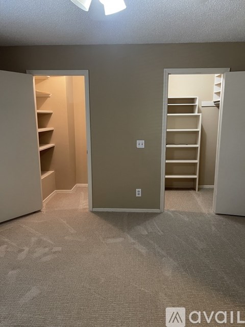 A room with a carpeted floor and a closet with shelves.
