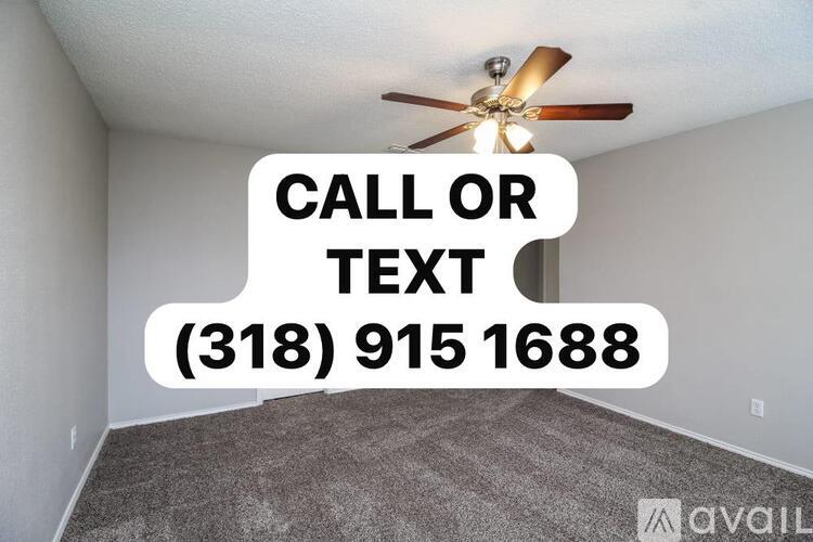 A room with a carpeted floor and a ceiling fan, with a sign that says "CALL OR TEXT (318) 915 1688".