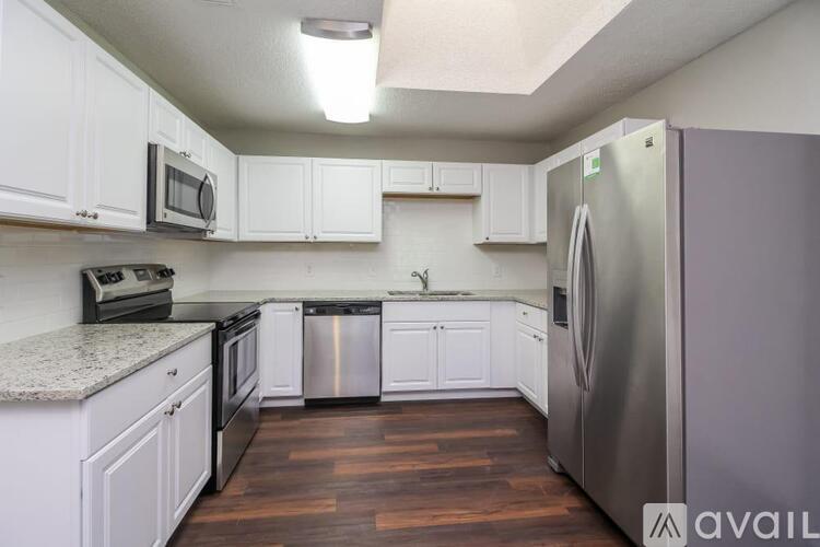 A kitchen with white cabinets and a stainless steel refrigerator.